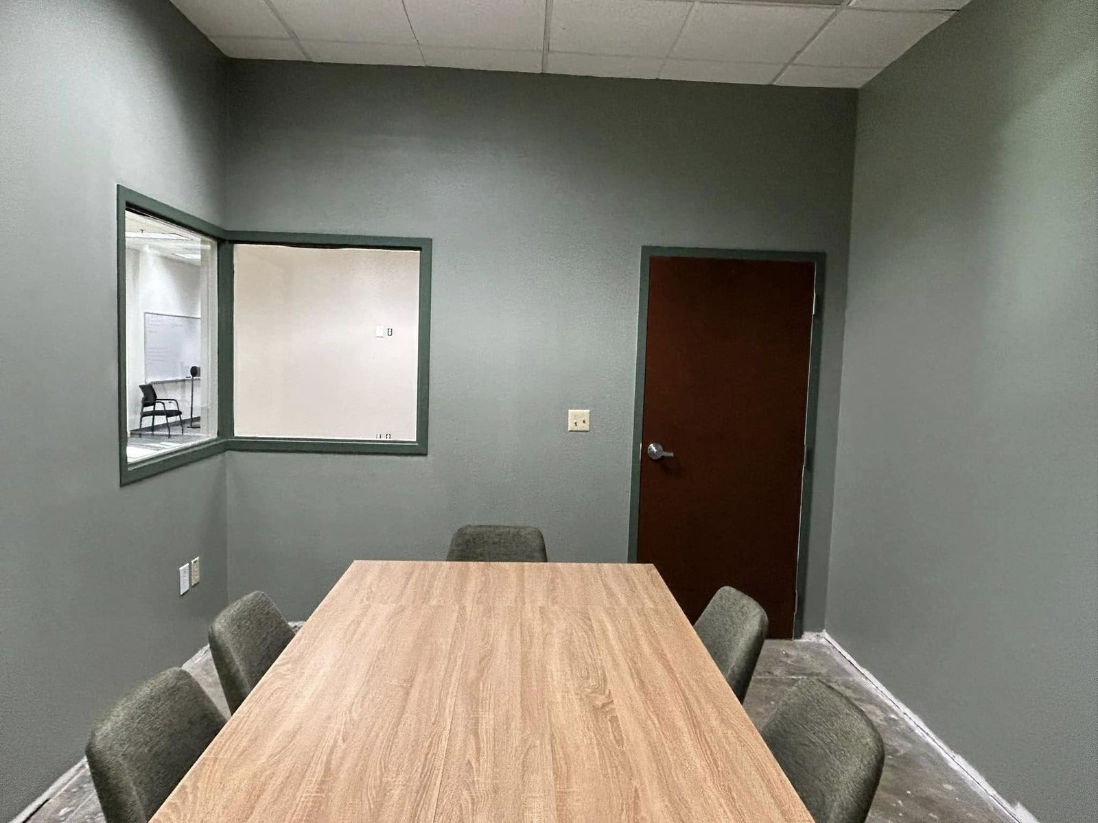 Conference room painted a muted green-gray with a long wood table