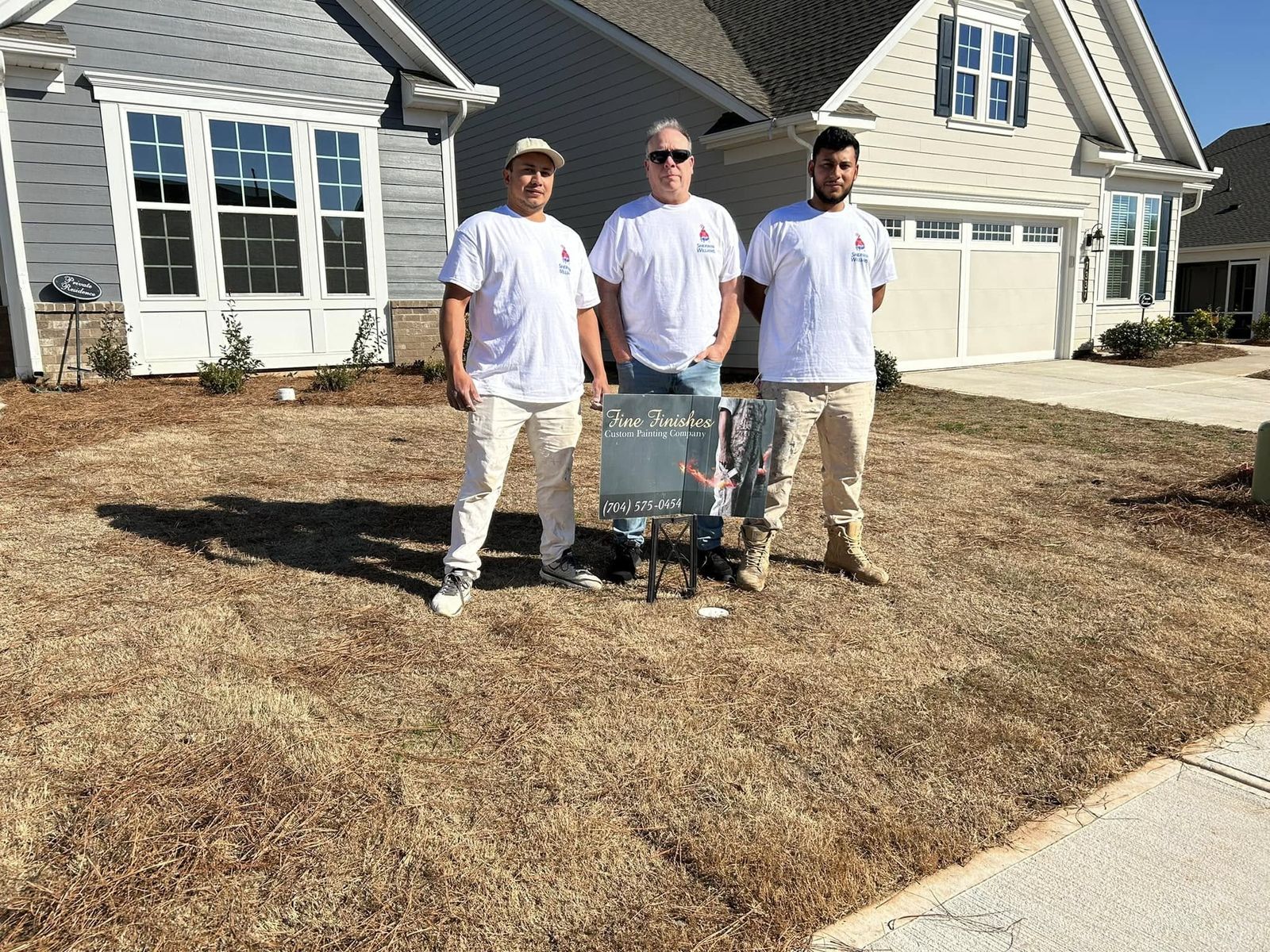 Three Fine Finishes painters in white shirts standing in front of a home