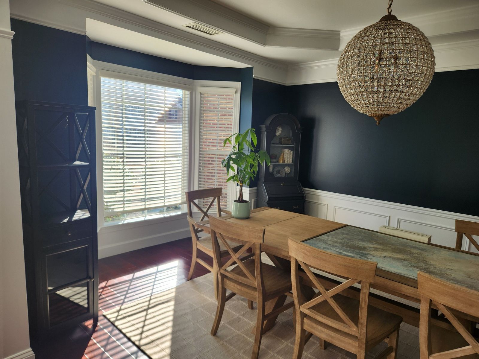 Navy dining room with white trim seen from the bay window side