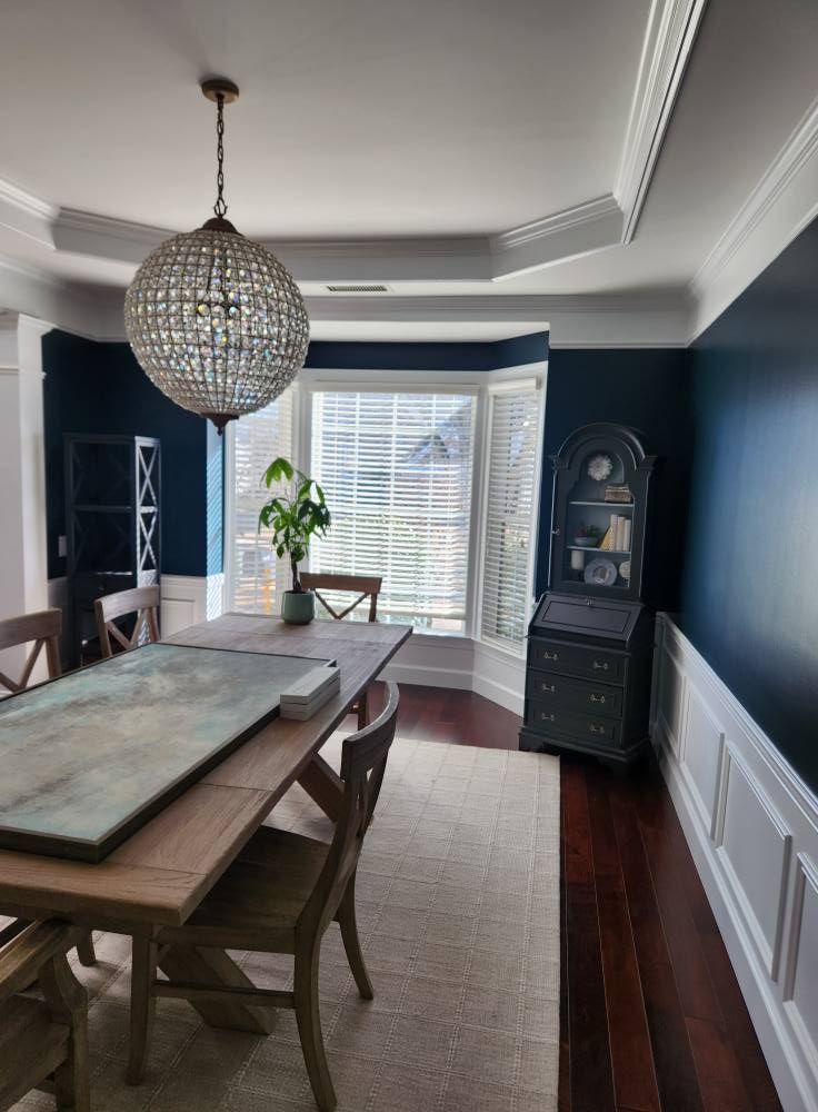 Dining room with navy walls above white wainscoting and a globe pendant
