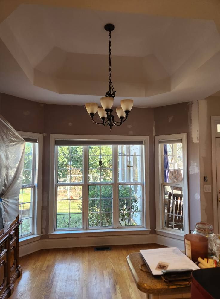 Dining area with a painted tray ceiling, bay windows and a chandelier