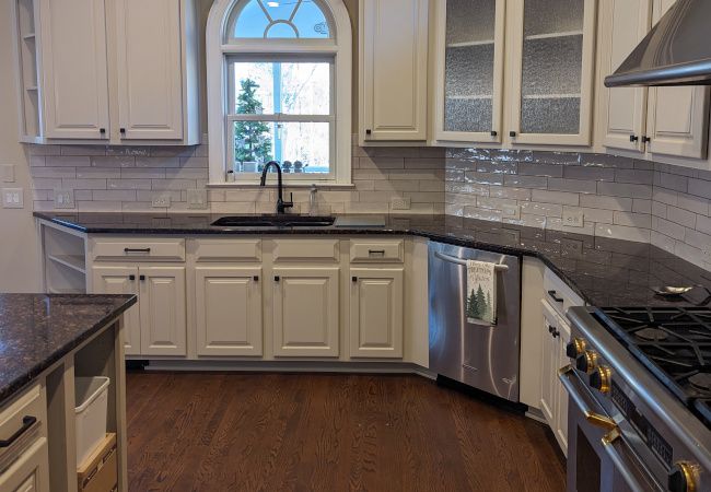 Kitchen with cream painted cabinets under an arched window