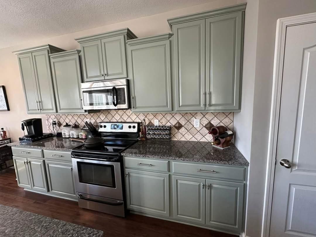 Kitchen cabinets painted sage green with a tile backsplash