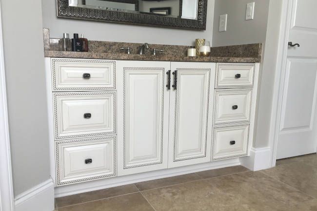White painted bathroom vanity with dark hardware and a granite top